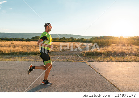 Triathlete in professional gear running early in the morning, preparing for a marathon, dedication to sport and readiness to take on the challenges of a marathon.  114979178