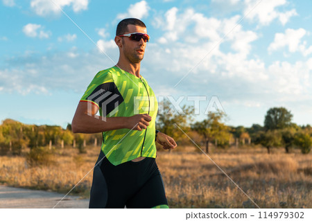 Triathlete in professional gear running early in the morning, preparing for a marathon, dedication to sport and readiness to take on the challenges of a marathon. Triathlete in professional gear running early in the morning, preparing for a marathon, dedication to sport and readiness to take on the challenges of a marathon. 114979302