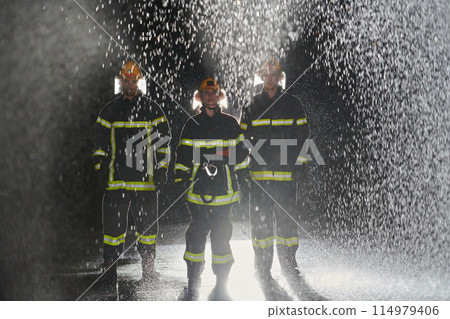 A group of professional firefighters marching through the rainy night on a rescue mission, their determined strides and fearless expressions reflecting their unwavering bravery and unwavering 114979406