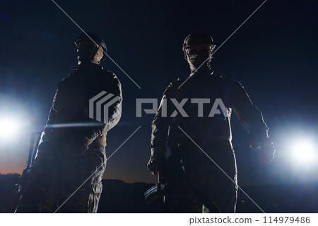 Two professional soldiers marching through the dark of night on a dangerous mission, epitomizing their unwavering bravery, unwavering teamwork, and the high-stakes intensity of their specialized Two professional soldiers marching through the dark of night on a dangerous mission, epitomizing their unwavering bravery, unwavering teamwork, and the high-stakes intensity of their specialized 114979486