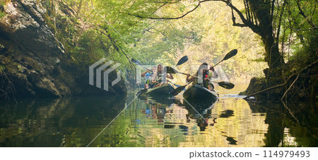 A group of friends enjoying having fun and kayaking while exploring the calm river, surrounding forest and large natural river canyons 114979493