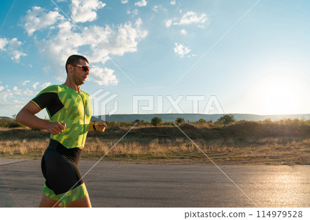 Triathlete in professional gear running early in the morning, preparing for a marathon, dedication to sport and readiness to take on the challenges of a marathon. Triathlete in professional gear running early in the morning, preparing for a marathon, dedication to sport and readiness to take on the challenges of a marathon. 114979528