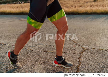 Closeup of muscular legs of a triathlete in professional equipment running early in the morning, preparing for a marathon, dedication to sports and readiness for marathon challenges Closeup of muscular legs of a triathlete in professional equipment running early in the morning, preparing for a marathon, dedication to sports and readiness for marathon challenges 114979767