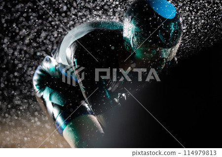 A triathlete braving the rain as he cycles through the night, preparing himself for the upcoming marathon. The blurred raindrops in the foreground and the dark, moody atmosphere in the background add A triathlete braving the rain as he cycles through the night, preparing himself for the upcoming marathon. The blurred raindrops in the foreground and the dark, moody atmosphere in the background add 114979813
