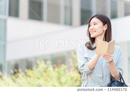 A woman or businesswoman filling out a diary, memo pad, notebook, schedule book, or planner 114980178