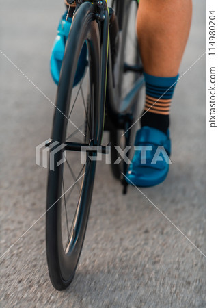Close up of the pedals of a bicycle being ridden by a professional triathlete preparing for training 114980204