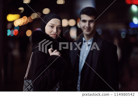 Happy multicultural business couple walking together outdoors in an urban city street at night near a jewelry shopping store window. 114980542