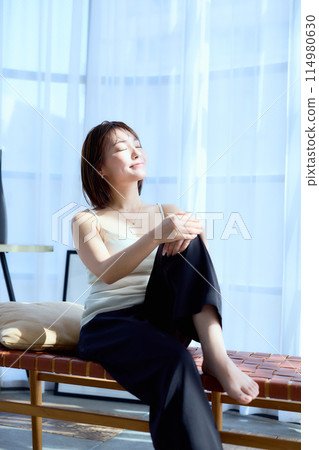 一個女人坐在房間的椅子上沐浴在早晨的陽光下 114980630