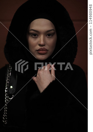 Muslim woman walking on an urban city street on a cold winter night wearing hijab Muslim woman walking on an urban city street on a cold winter night wearing hijab 114980948