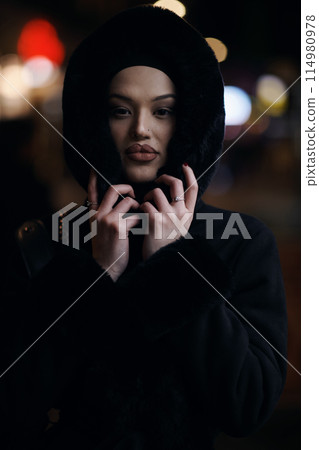 Muslim woman walking on an urban city street on a cold winter night wearing hijab 114980978
