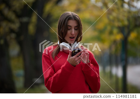 Sporty woman checks smartphone before doing some exercises listens music from a playlist 114981181