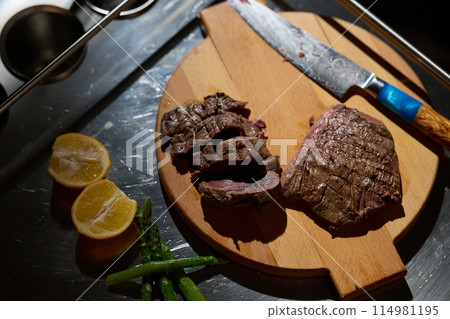 Close-up shot, a professional chef expertly prepares a delicious steak using modern cooking techniques, showcasing culinary excellence and precision in the art of gourmet cuisine 114981195