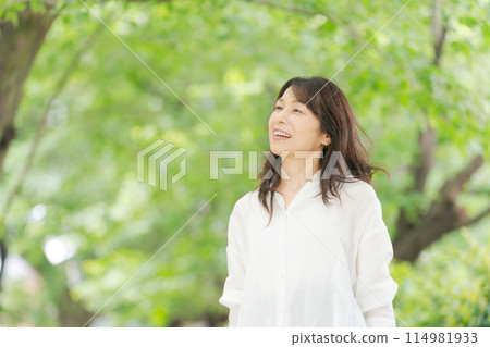 Middle-aged woman smiling in the park Middle-aged woman smiling in the park 114981933