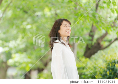 Middle-aged woman smiling in the park Middle-aged woman smiling in the park 114981934