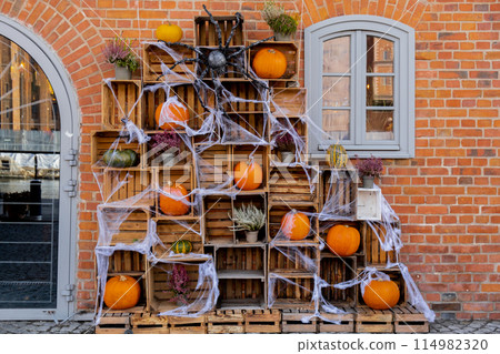 Exterior design cozy atmospheric halloween pumpkins in wooden boxes decorated on porch. Autumn leaves and fall flowers celebration holiday Thanksgiving October season 114982320