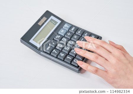 Hands of a woman using a calculator 114982334