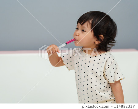 baby girl takes syrup medicine with syringe. sick toddler baby girl takes syrup medicine with syringe. sick toddler 114982337