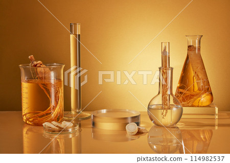 Template photo of ginseng theme in laboratory was shot from front against yellow background, glass podium and lab instrument containing extract from ginseng and raw ginseng neatly arranged on table 114982537