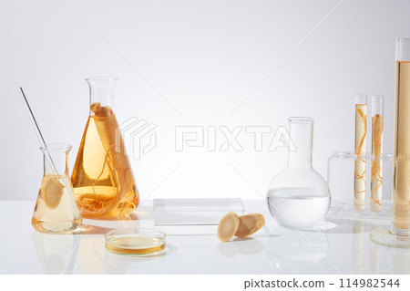 Ginseng and laboratory utensils concept photo was shot from front view with glass showcase pedestal placed in center for displaying herb extract products. Space for adding text or design elements Ginseng and laboratory utensils concept photo was shot from front view with glass showcase pedestal placed in center for displaying herb extract products. Space for adding text or design elements 114982544
