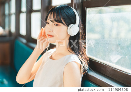 Woman listening to music by train Woman listening to music by train 114984808
