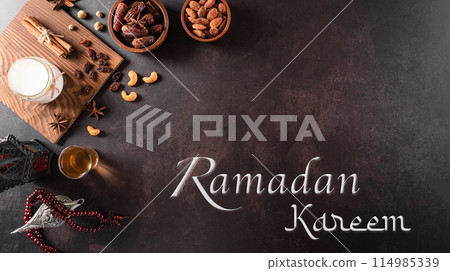 Table top view image of decoration Ramadan Kareem, dates fruit, aladdin lamp, milk and rosary beads on dark stone background. Flat lay with copy space. 114985339