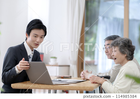 A visiting salesman talking to a senior couple 114985384