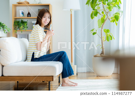 A young woman operating a smartphone in a room A young woman operating a smartphone in a room 114987277