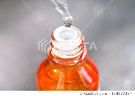 Dropping serum collagen moisturizer of face into clear yellow bottle soft light background. Protector skin Treatment facial essence oil, Vitamin C. Beauty and spa Concept Dropping serum collagen moisturizer of face into clear yellow bottle soft light background. Protector skin Treatment facial essence oil, Vitamin C. Beauty and spa Concept 114987384