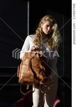 beautiful curly blond hair woman posing with a leather backpack beautiful curly blond hair woman posing with a leather backpack 114987446