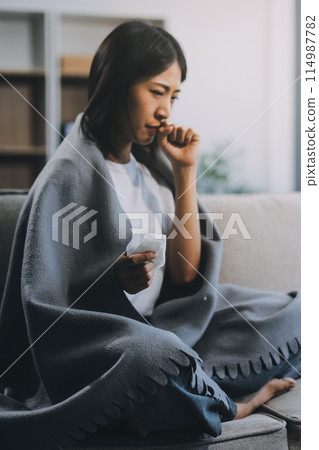 Upset woman frustrated by problem with work or relationships, sitting on couch, embracing knees, covered face in hand, feeling despair and anxiety, loneliness, having psychological trouble 114987782
