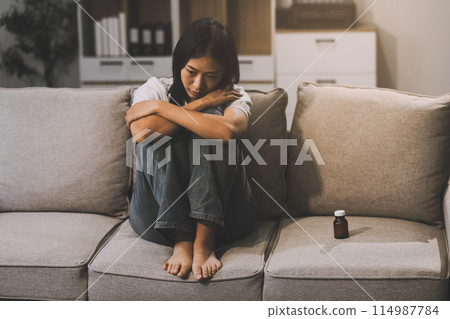 Upset woman frustrated by problem with work or relationships, sitting on couch, embracing knees, covered face in hand, feeling despair and anxiety, loneliness, having psychological trouble 114987784