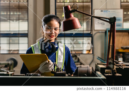 Portrait happy engineer worker with safety eyes protection glasses professional working with metal lathe milling machine heavy industry factory. 114988116