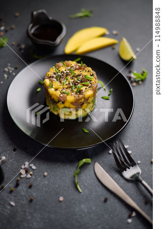 Traditional tuna and mango tartare on black ceramic plate 114988848
