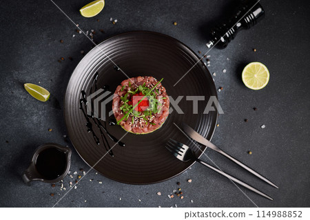 Tuna and avocado tartare on a dark ceramic plate Tuna and avocado tartare on a dark ceramic plate 114988852