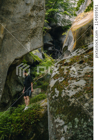 man tourist hiking by rocks on forest 114989561
