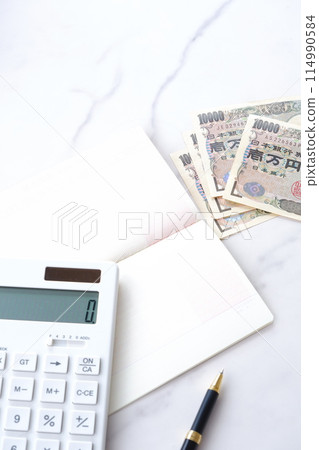 銀行存摺、10,000日元鈔票和計算機放在桌上打開 114990584