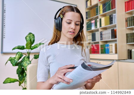Webcam view of teenage girl, high school student, in headphones, talking to camera 114992849