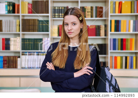 Portrait of high school student girl with backpack in library classroom 114992893