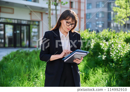 Portrait of business mature woman with digital tablet, outdoor Portrait of business mature woman with digital tablet, outdoor 114992910
