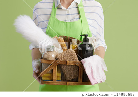Modern female in green apron and rubber gloves isolated on green Modern female in green apron and rubber gloves isolated on green 114993692