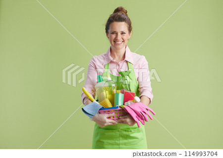 happy woman in green apron and rubber gloves isolated on green happy woman in green apron and rubber gloves isolated on green 114993704