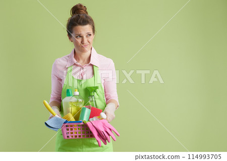 unhappy modern housewife isolated on green background unhappy modern housewife isolated on green background 114993705