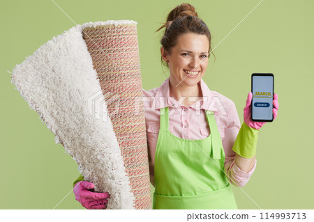 happy woman showing smartphone screen isolated on green 114993713