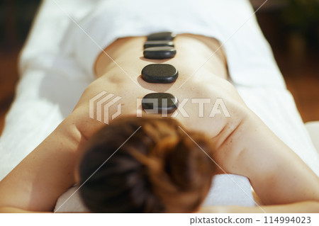 Female having hot stone massage and laying on massage table 114994023
