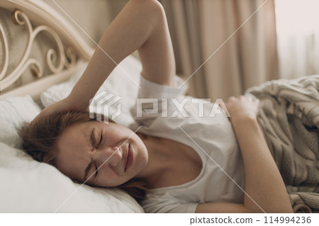 Young woman suffering with headache flu ill sick disease cold at home indoor lying on bed top view Young woman suffering with headache flu ill sick disease cold at home indoor lying on bed top view 114994236