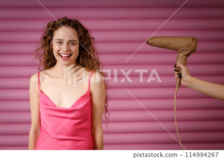Young positive smiling woman receives surprise gift hand hold hair dryer wrapped in rustic beige craft paper. Black Friday concept on pink background. Young positive smiling woman receives surprise gift hand hold hair dryer wrapped in rustic beige craft paper. Black Friday concept on pink background. 114994267