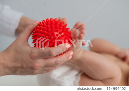 A doctor massages a baby's foot using a spiked ball. 114994402