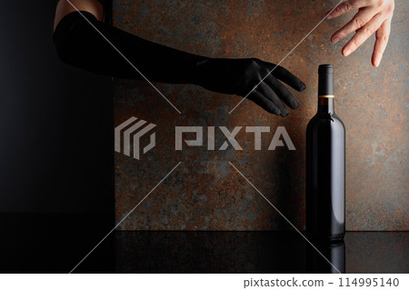 Hands in reaches for a bottle of red wine. 114995140
