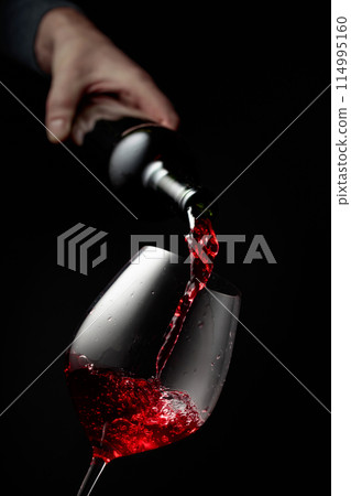 Pouring red wine in a glass goblet. 114995160