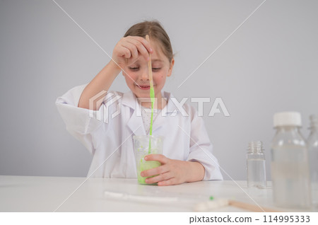 Caucasian girl doing chemical experiments on a white background. Making slime. 114995333